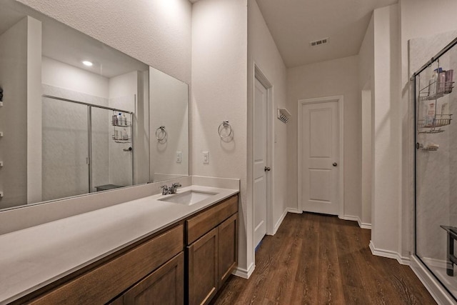 bathroom featuring vanity, wood-type flooring, and a shower with shower door