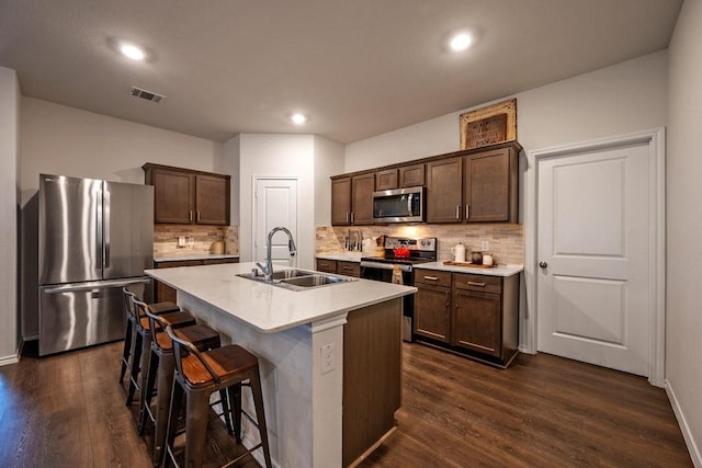 kitchen with stainless steel appliances, sink, dark hardwood / wood-style flooring, and a kitchen island with sink