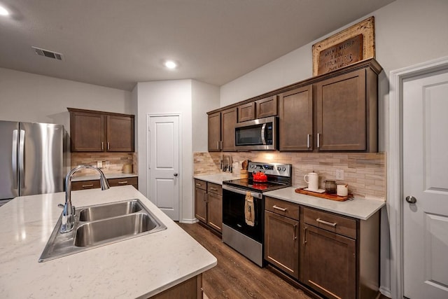 kitchen with dark brown cabinetry, appliances with stainless steel finishes, dark hardwood / wood-style floors, and sink