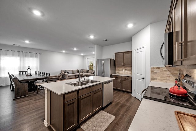 kitchen featuring dark brown cabinetry, sink, a center island with sink, and appliances with stainless steel finishes