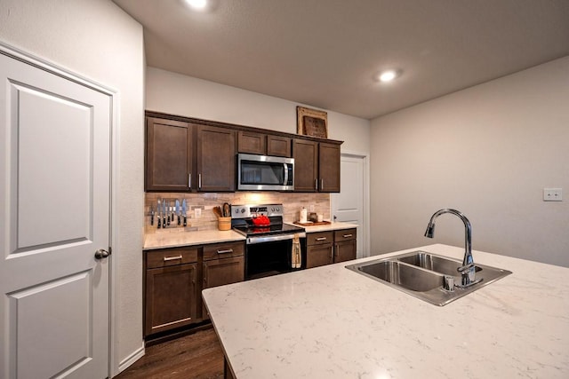 kitchen with dark brown cabinetry, sink, appliances with stainless steel finishes, dark hardwood / wood-style flooring, and backsplash