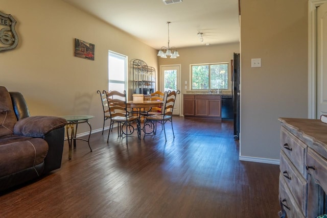 dining space with sink, dark wood-type flooring, and a chandelier