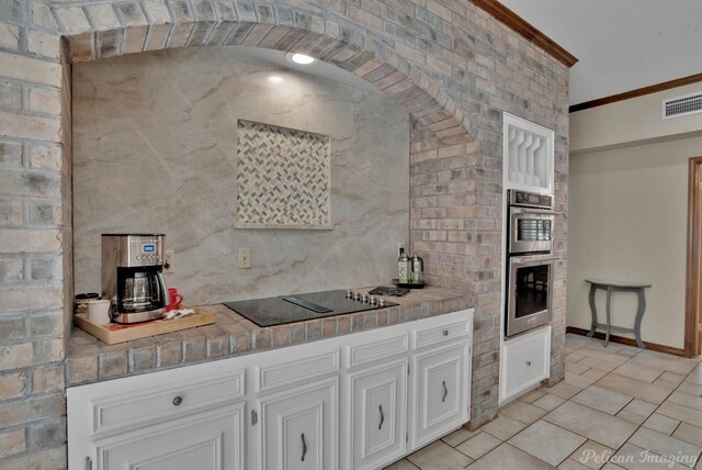 kitchen with appliances with stainless steel finishes, sink, white cabinets, ornamental molding, and light stone countertops