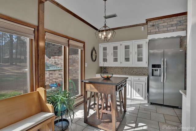 kitchen with crown molding, decorative light fixtures, stainless steel fridge with ice dispenser, white cabinets, and backsplash