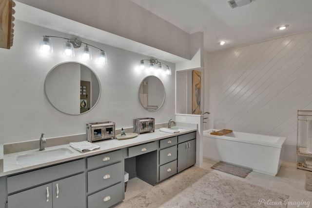 bathroom featuring double vanity, a freestanding tub, and a sink