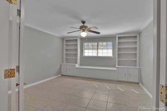 empty room with ornamental molding, built in shelves, light tile patterned floors, and baseboards