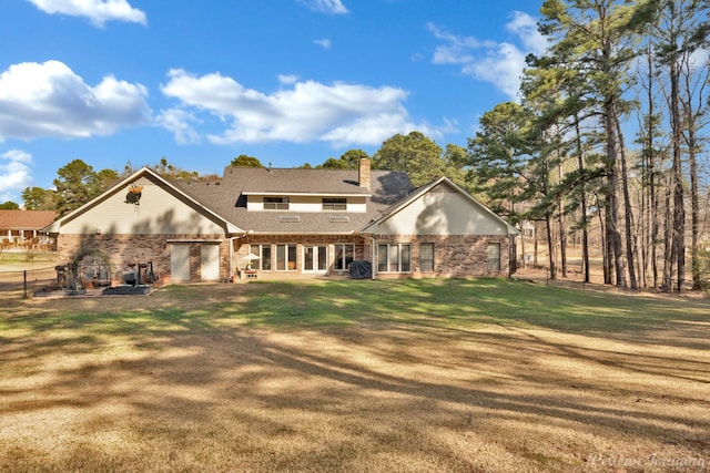 rear view of property with a chimney, a lawn, and brick siding