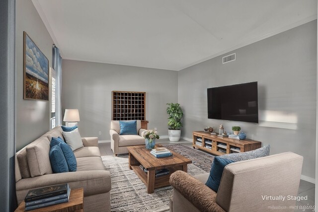 living area featuring baseboards, visible vents, and ornamental molding