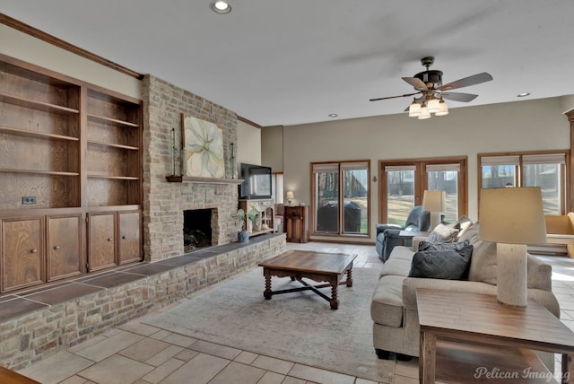 living room with a fireplace, light tile patterned floors, ceiling fan, crown molding, and built in shelves