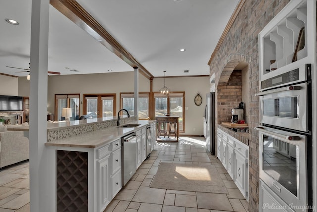 kitchen with wine cooler, hanging light fixtures, appliances with stainless steel finishes, white cabinetry, and a sink