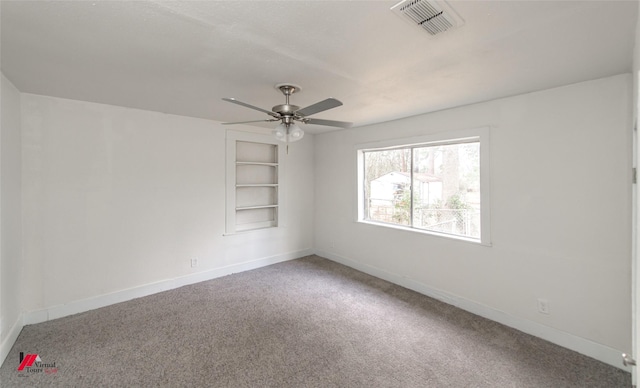 carpeted spare room with built in shelves and ceiling fan