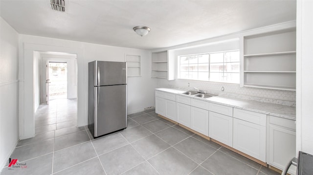 kitchen with sink, stainless steel refrigerator, white cabinets, and light tile patterned flooring