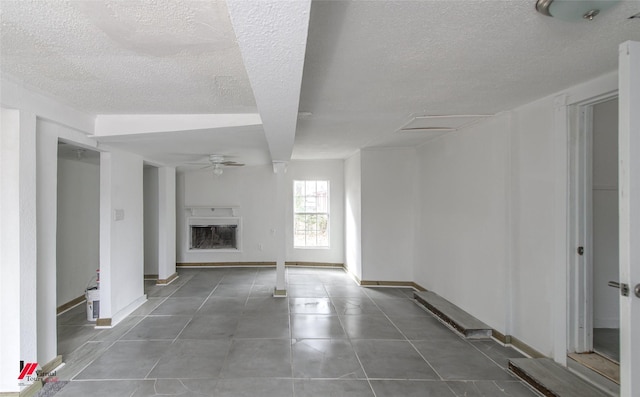 unfurnished living room with tile patterned flooring, a textured ceiling, and ceiling fan