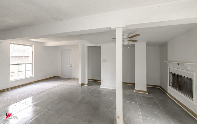 interior space with ceiling fan, dark tile patterned flooring, and a textured ceiling