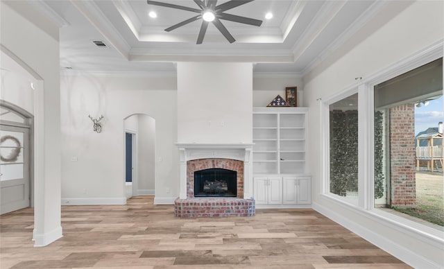 unfurnished living room featuring crown molding, a high ceiling, a brick fireplace, and light hardwood / wood-style flooring