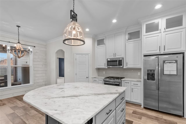 kitchen with a kitchen island, white cabinetry, appliances with stainless steel finishes, and decorative light fixtures