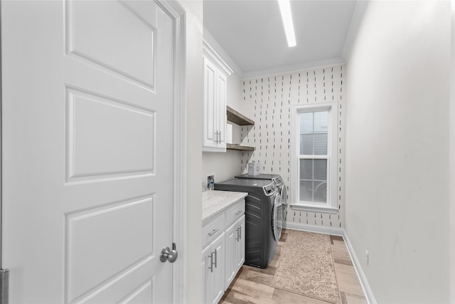 clothes washing area with cabinets, separate washer and dryer, and light wood-type flooring