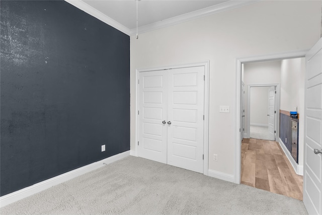 unfurnished bedroom featuring ornamental molding, carpet flooring, and a closet