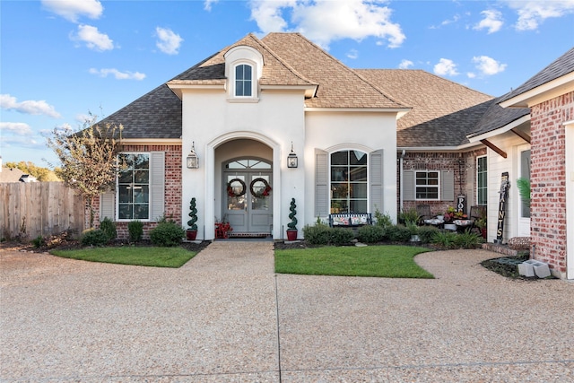 french country home with a front yard and french doors