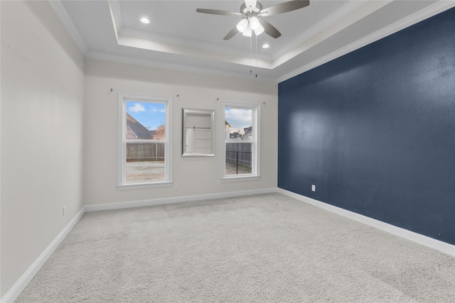 carpeted spare room with ceiling fan, ornamental molding, and a tray ceiling