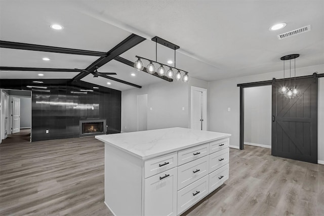 kitchen with white cabinetry, a barn door, a center island, and decorative light fixtures