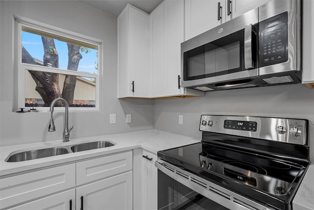 kitchen featuring white cabinetry, sink, light stone countertops, and appliances with stainless steel finishes