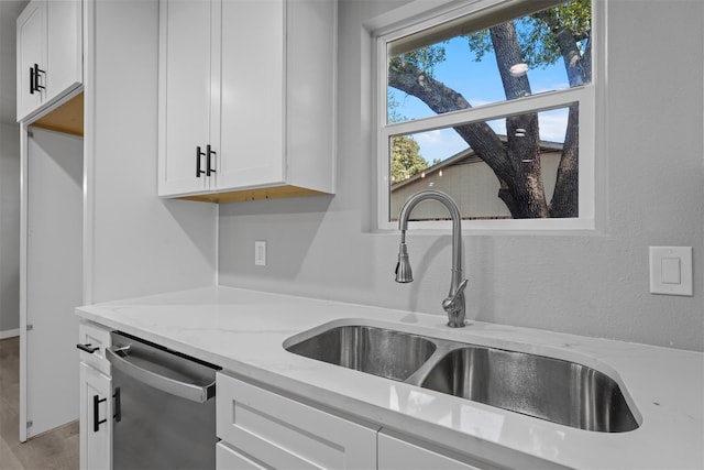 kitchen with light stone counters, stainless steel dishwasher, sink, and white cabinets