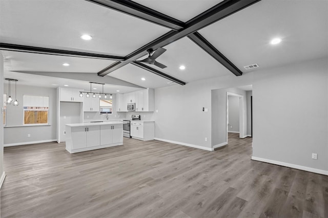 unfurnished living room featuring ceiling fan, light hardwood / wood-style floors, and vaulted ceiling with beams