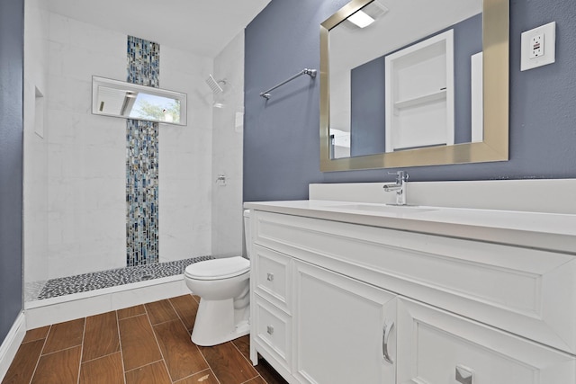 bathroom featuring vanity, toilet, and a tile shower