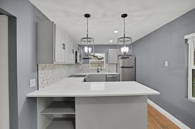 kitchen featuring stainless steel appliances, gray cabinets, pendant lighting, and kitchen peninsula