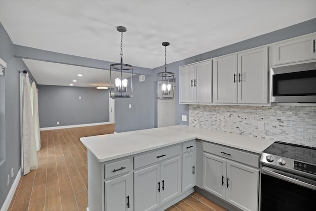 kitchen with stainless steel appliances, kitchen peninsula, hanging light fixtures, and backsplash