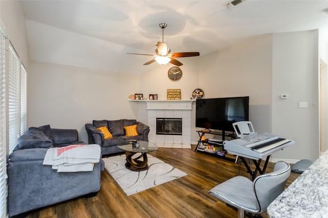 living area featuring visible vents, a ceiling fan, a tiled fireplace, lofted ceiling, and dark wood-style floors