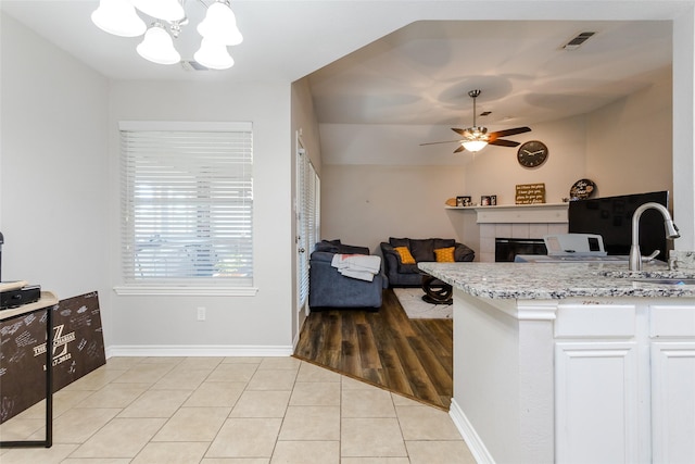 kitchen featuring light tile patterned floors, visible vents, open floor plan, white cabinets, and a tile fireplace