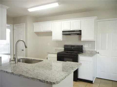 kitchen with sink, light tile patterned floors, white cabinets, and light stone counters