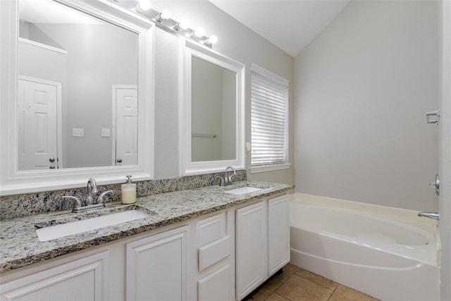 bathroom featuring a bath, tile patterned flooring, vaulted ceiling, and a sink