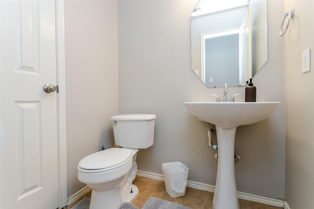 bathroom featuring tile patterned flooring, baseboards, and toilet