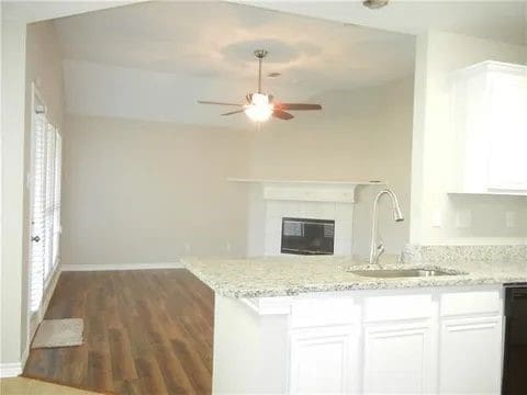 kitchen with light stone counters, sink, and white cabinets