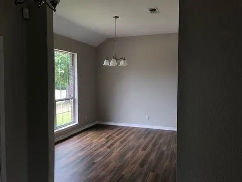 spare room with dark hardwood / wood-style flooring, lofted ceiling, and a chandelier