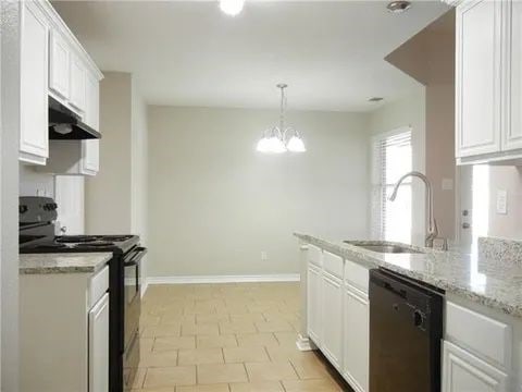 kitchen featuring pendant lighting, sink, black appliances, and white cabinets