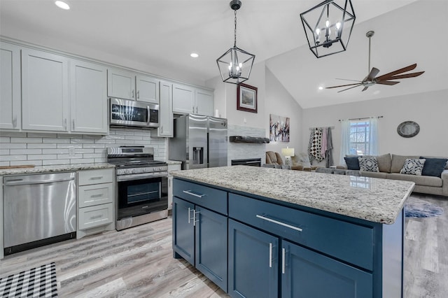 kitchen with pendant lighting, blue cabinetry, white cabinetry, stainless steel appliances, and a kitchen island