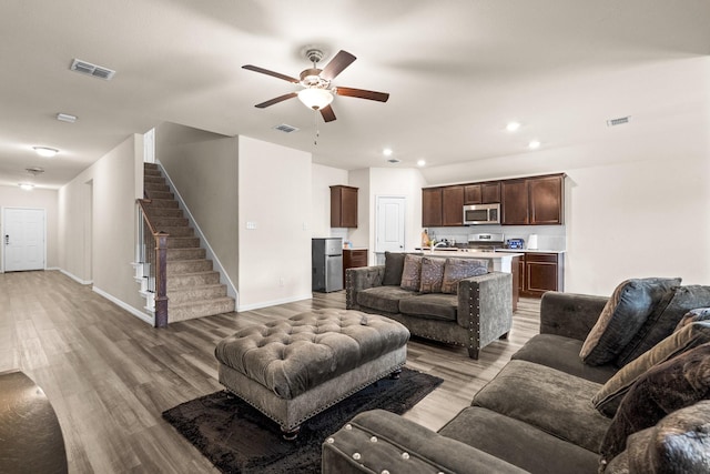 living room featuring ceiling fan, sink, and light hardwood / wood-style floors