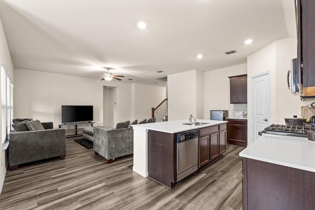 kitchen with dark hardwood / wood-style floors, stainless steel appliances, sink, and an island with sink