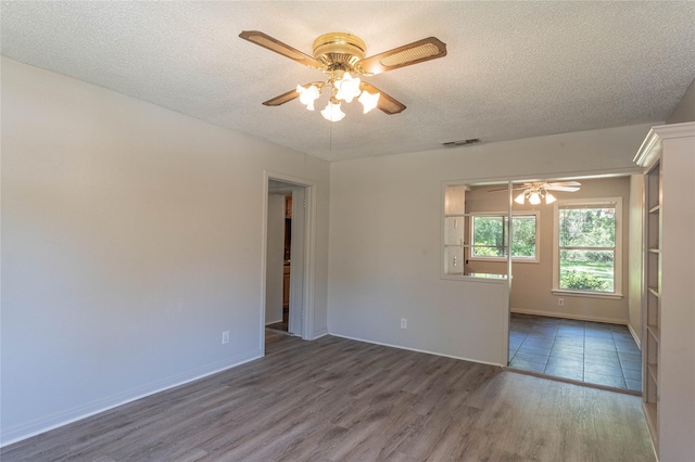 spare room featuring ceiling fan, dark wood-type flooring, and a textured ceiling