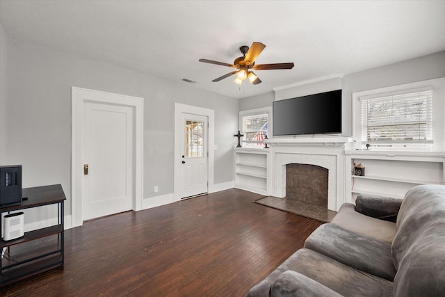 living room featuring ceiling fan, dark hardwood / wood-style flooring, and a brick fireplace