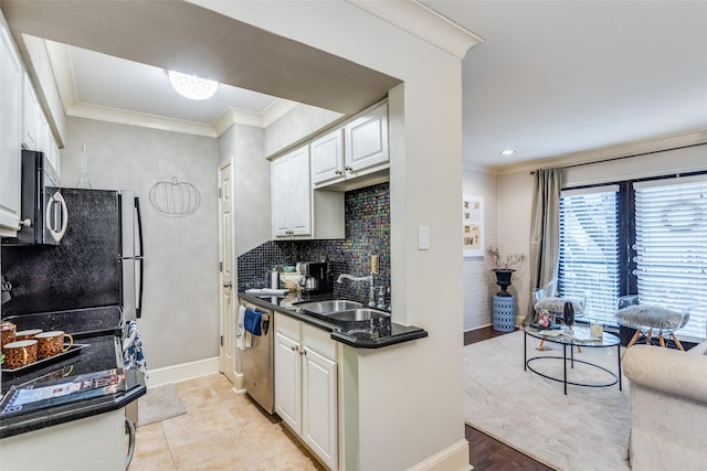 kitchen with appliances with stainless steel finishes, tasteful backsplash, sink, white cabinets, and ornamental molding