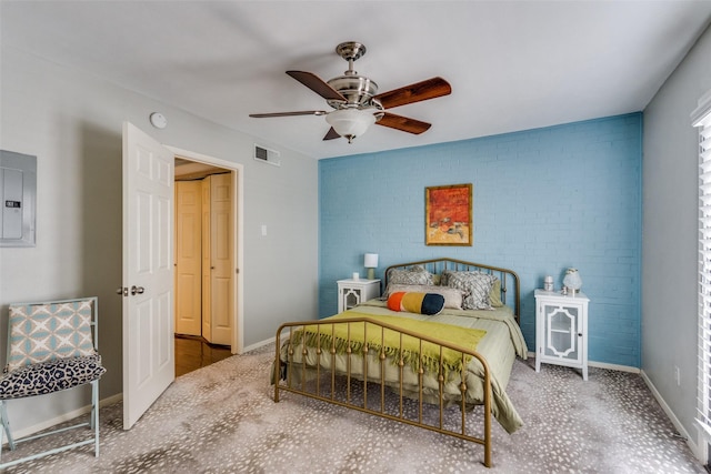 carpeted bedroom featuring electric panel, ceiling fan, and brick wall