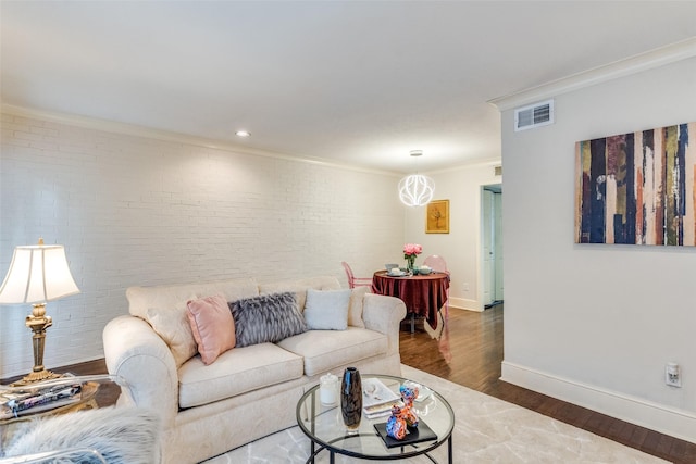 living room featuring crown molding, brick wall, and hardwood / wood-style floors