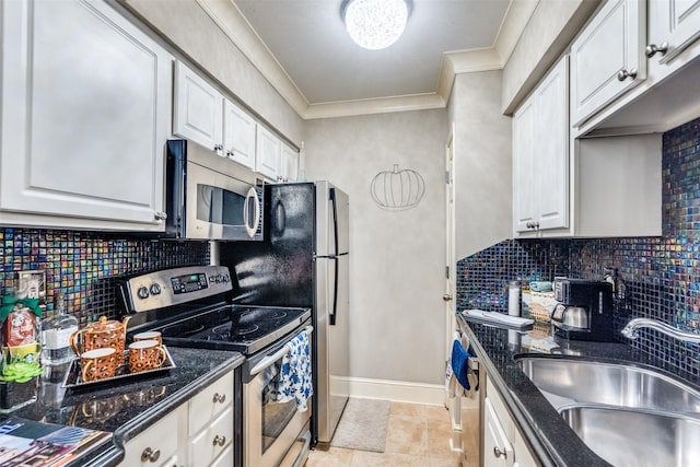 kitchen with appliances with stainless steel finishes, white cabinetry, sink, dark stone counters, and crown molding