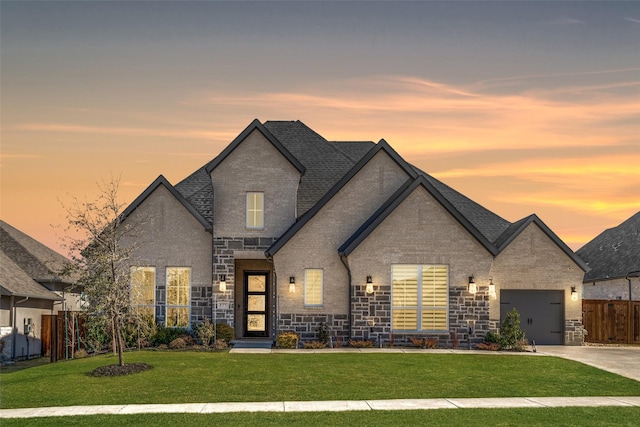 french provincial home with a garage and a lawn