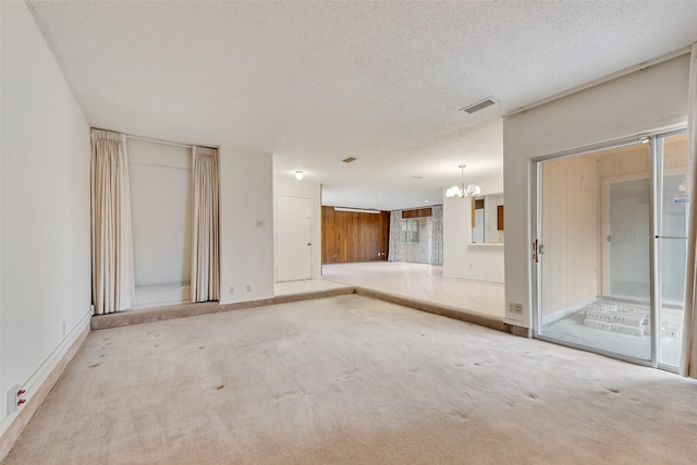 carpeted spare room with a textured ceiling and a notable chandelier